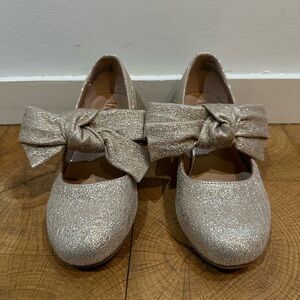Girls sparkly gold heels with bows.